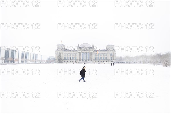 A person stands in front of the Bundestag in the driving snow in Berlin