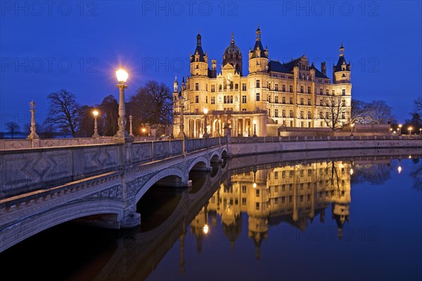 Illuminated Schwerin Castle with the castle bridge to the castle island in the evening