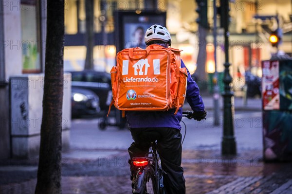 A driver of the delivery service Lieferando rides his bicycle through the old town of Duesseldorf