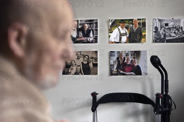 Subject: Old man sitting in front of a wall with pictures