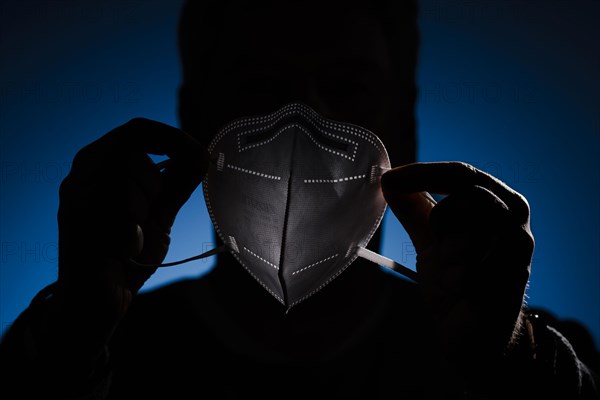 A man holds an FFP2 protective mask in front of his face. Berlin