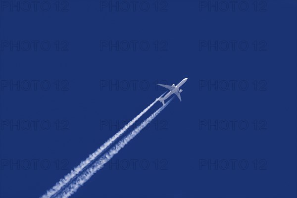 White airliner contrails against blue sky