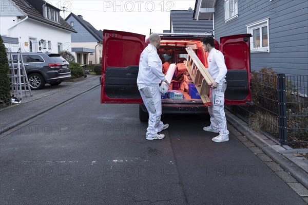 Subject: Master painter and apprentice loading a van with work materials