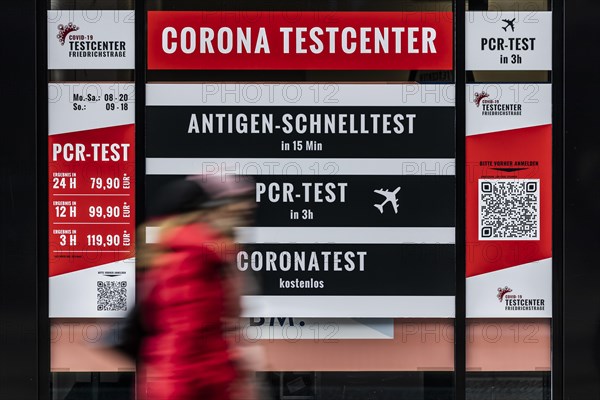 A person stands out in front of large-scale advertising for a Corona test centre in Berlin