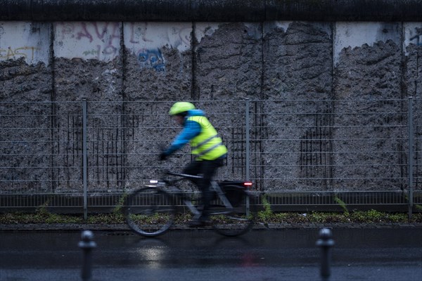 A cyclist stands out in front of the Berlin Wall in Berlin