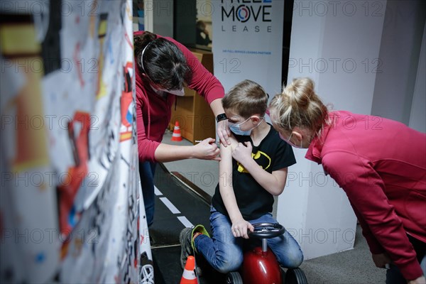 A boy is vaccinated by a doctor with the BioNTech Pfizer children's vaccine at a COVID-19 vaccination and testing centre at Autohaus Olsen in Iserlohn