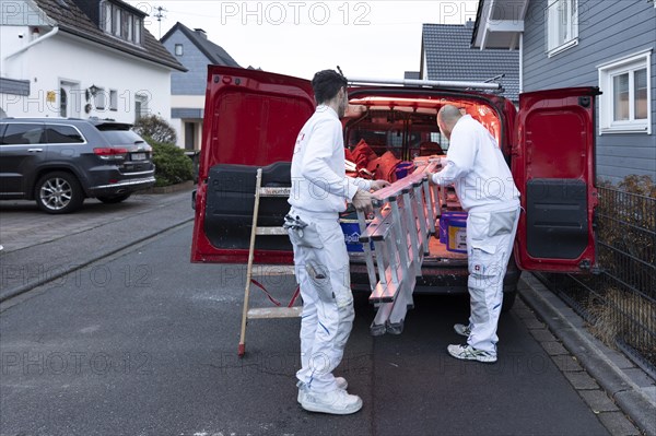 Subject: Master painter and apprentice loading a van with work materials