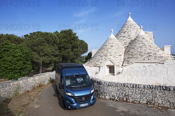 Motorhome drives past trulli dwelling