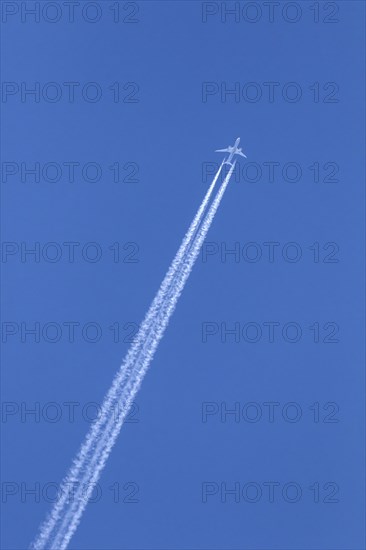 Commercial passenger twin-engine jet airliner in flight showing contrails