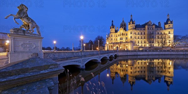 Illuminated Schwerin Castle with the castle bridge to the castle island in the evening