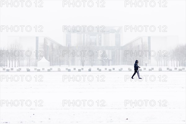 A person is silhouetted in front of the Chancellery in the driving snow in Berlin
