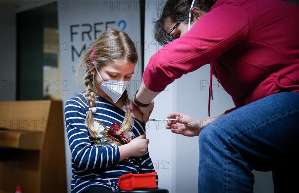 A girl is vaccinated by a doctor with the BioNTech Pfizer children's vaccine at a COVID-19 vaccination and testing centre at the Olsen car dealership in Iserlohn