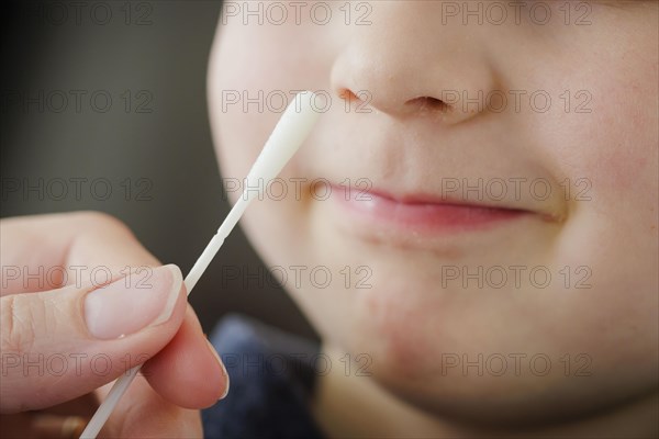 Symbolic photo on the subject of nasal testing for young children. A mother takes a swab from her child's nose. Berlin