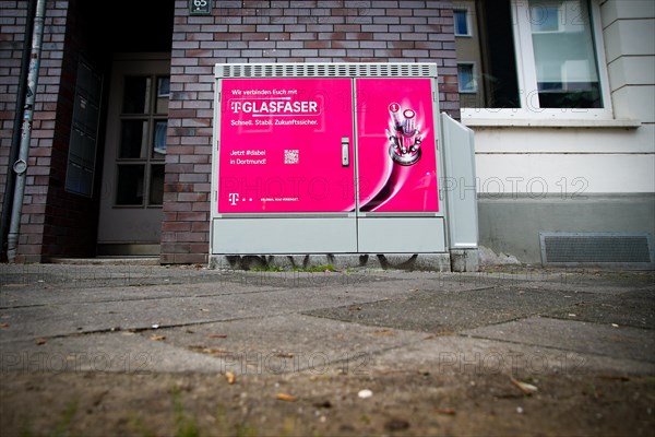 A Deutsche Telekom switch box is covered with a poster advertising fibre optics in Dortmund