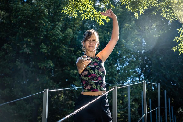 Woman practising tai chi with a sword on a bridge. She demonstrates great skill and concentration in her practice