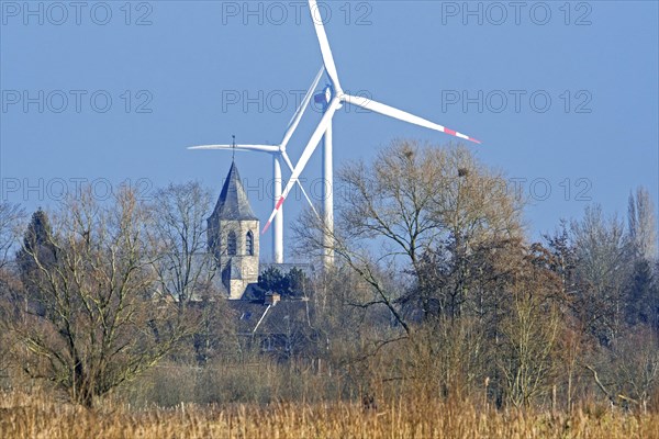 Church tower of the village Mariakerke near Ghent and wind turbines seen from nature reserve Bourgoyen-Ossemeersen in winter