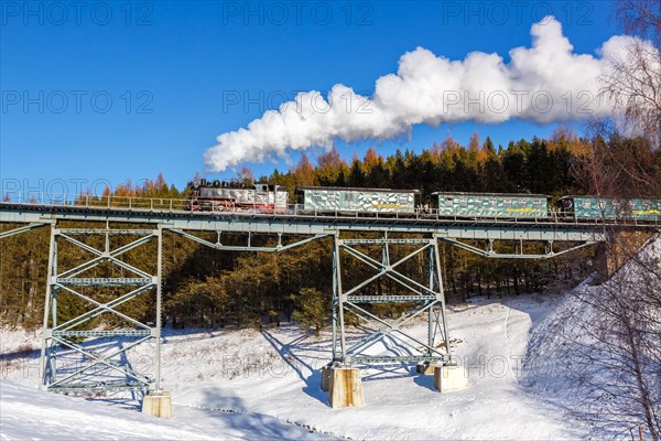 Steam train of the Fichtelbergbahn railway Steam locomotive on a bridge in winter in Oberwiesenthal