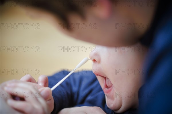 Symbolic photo on the subject of nasal testing for young children. A mother takes a swab from her child's nose. Berlin