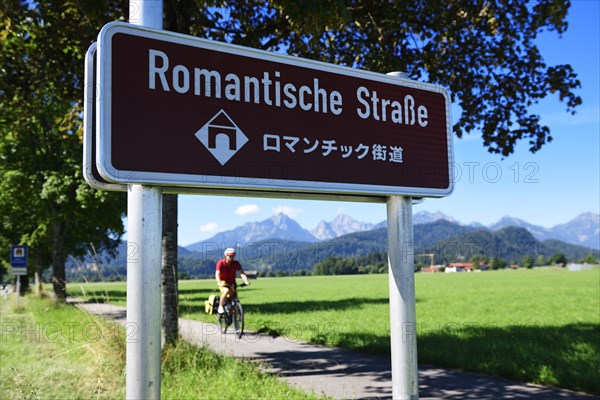 Cyclist in front of sign Romantic Road with translation in Japanese