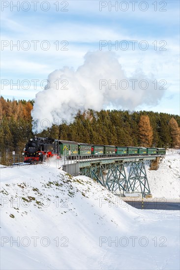 Steam train of the Fichtelbergbahn railway Steam locomotive on a bridge in winter in Oberwiesenthal