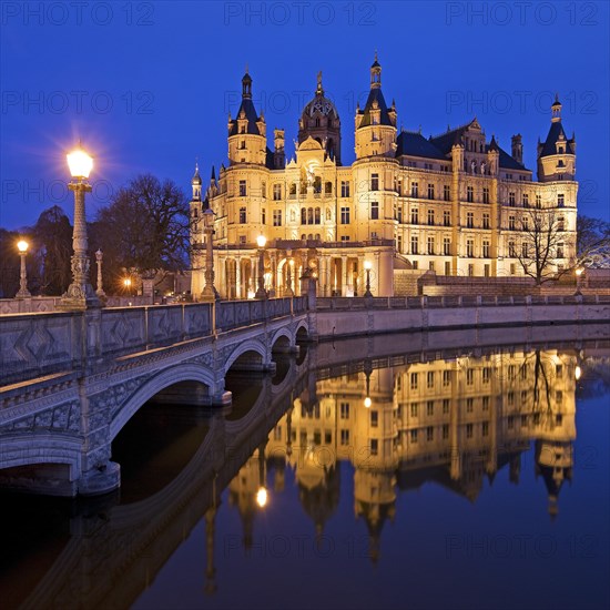 Illuminated Schwerin Castle with the castle bridge to the castle island in the evening