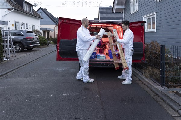 Subject: Master painter and apprentice loading a van with work materials