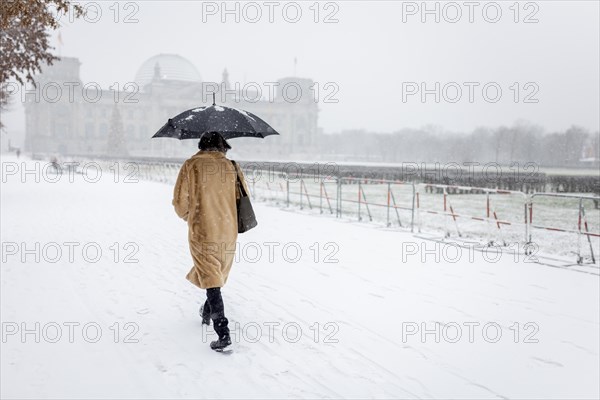 A person stands in front of the Bundestag in the driving snow in Berlin