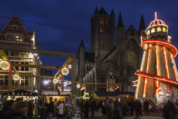 Illuminated helter skelter and people shopping at evening Christmas market in winter