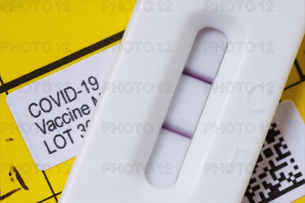 A positive SARS-CoV-2 Rapid Ag Antigen rapid test is on a vaccination book. Berlin