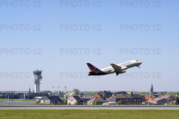 Control tower of Brussels Airport and the village Steenokkerzeel behind runway of Brussels Airlines while airplane is taking off