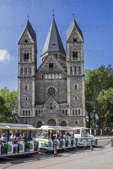 Tourists in little tourist train in front of the Temple neuf