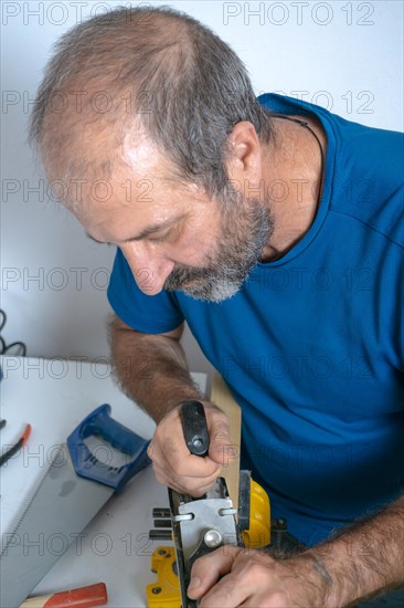 Top view of a bearded male carpenter planing wood with a hand planer isolated on white background