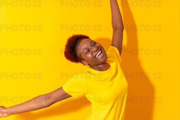 Young african american woman isolated on a yellow background smiling and dancing