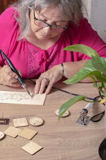 Front view of a woman burning a wooden board with a pyrographer