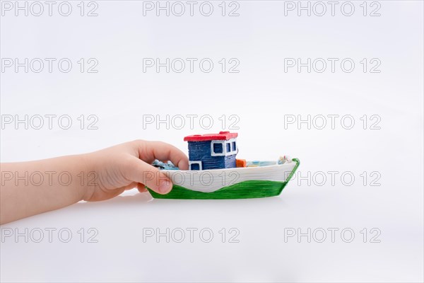 Little colorful model boat in hand on white background