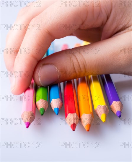 Hand holding color Pencils placed on a white background