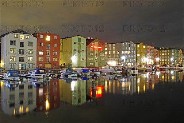 Brightly lit houses and pleasure boats reflected in a harbour basin at night