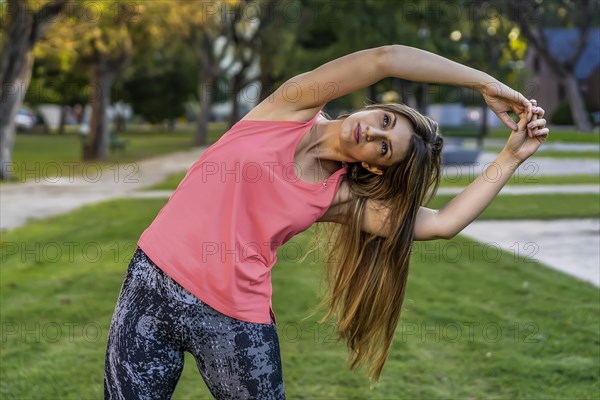 Attractive and healthy young woman doing stretching exercises outdoors