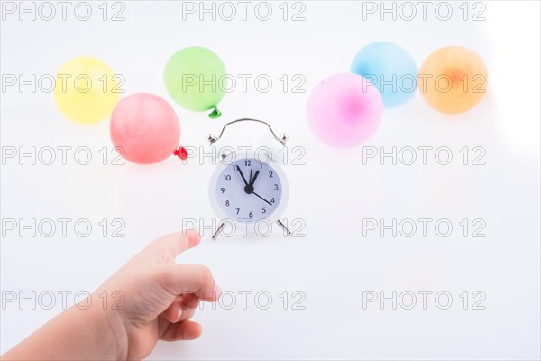 Hand pointing an alarm clock with balloons on the white background