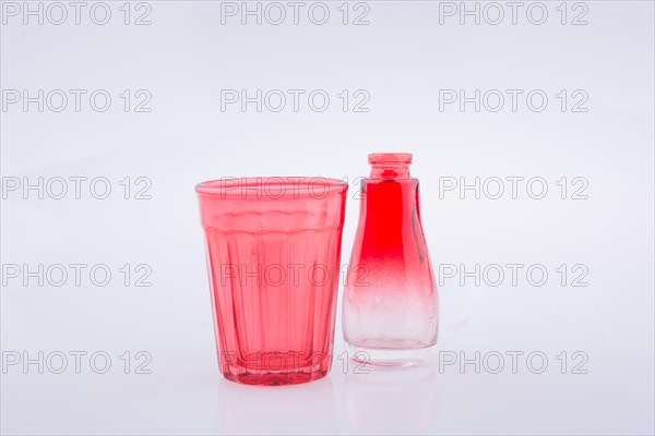 Little colorful bottle and a glass on a white background