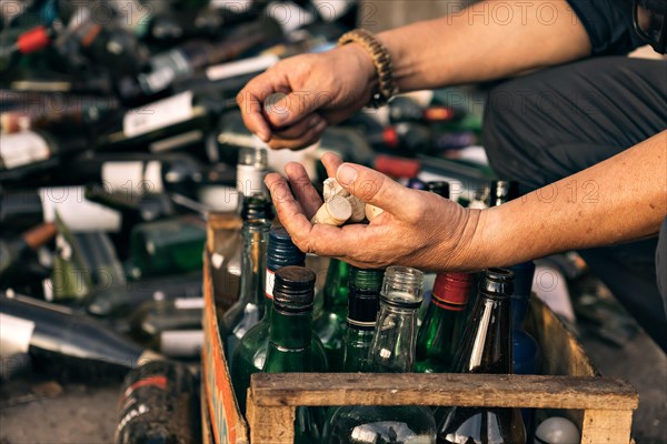 Close-up of a man's hands picking up glass bottle caps at a recycling centre. Concept of environmental conservation. Recycling. Voluntary work