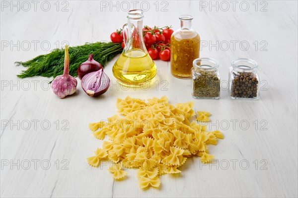 Uncooked pasta farfalline scattered on the table surrounded with ingredients