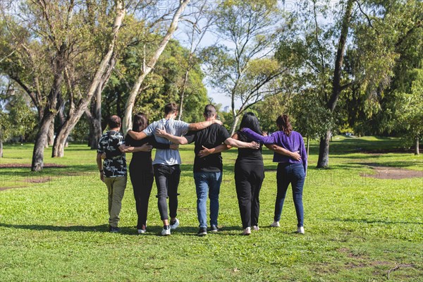 Rear view of a group of friends hugging while walking. Friendship and support concept