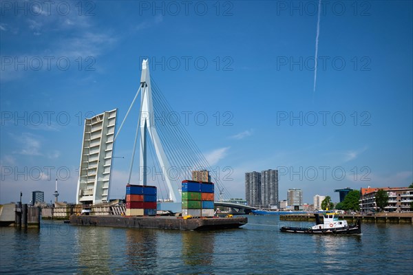 Tug boat towing barge with containers under open bascule part of Erasmusbrug bridge in Nieuwe Maas river. Rotterdam