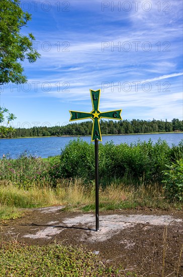 Old historical iron cross of paws with Masonic symbolism in a grove in front of Laeckoe Castle by Lake Vaenern