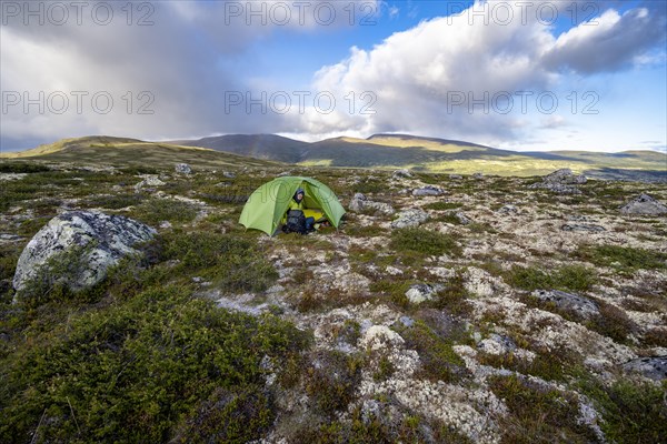Young man sitting in green tent