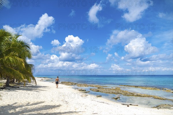 Athletic young man walking on a paradise beach. Concept Vacation