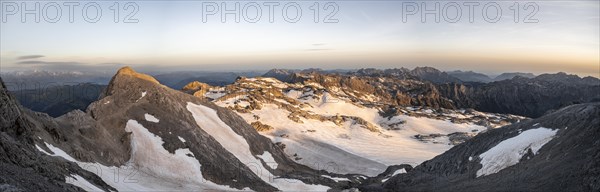 View of rocky plateau with snow and glacier at sunrise