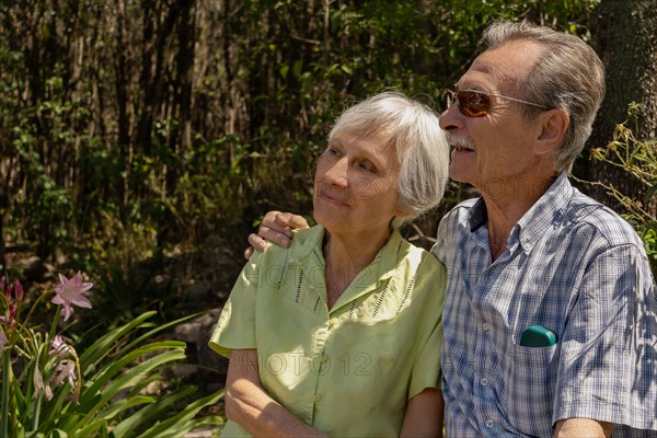 Elderly couple sitting hugging and enjoying time together outdoors. Concept health insurance