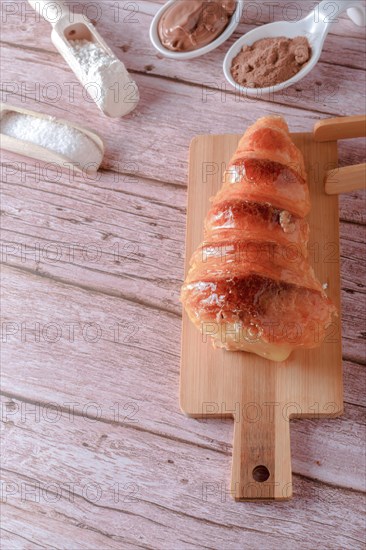 Puff pastry horn filled with pastry cream with some spoons with cocoa